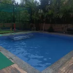 Outdoor swimming pool with safety fence and lush greenery - Misty Palace Villa, Lonavala. Alt Text: Private swimming pool at 5 BHK villa in Lonavala Misty Palace