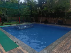 Outdoor swimming pool with safety fence and lush greenery - Misty Palace Villa, Lonavala